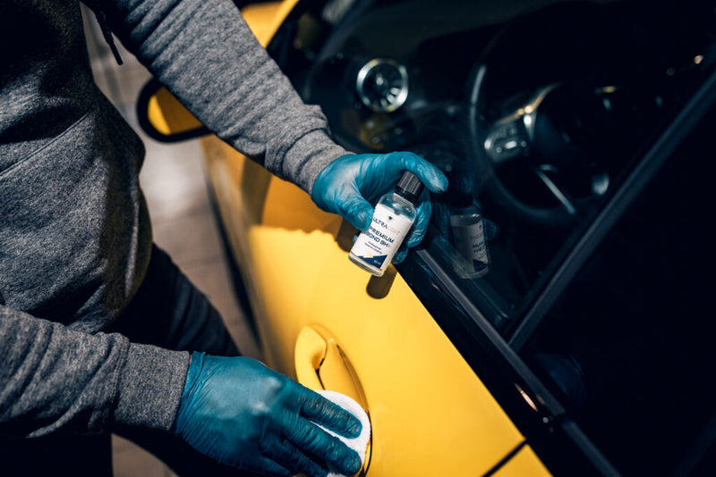 Ceramic coating bottle and applicator next to a detailed car
