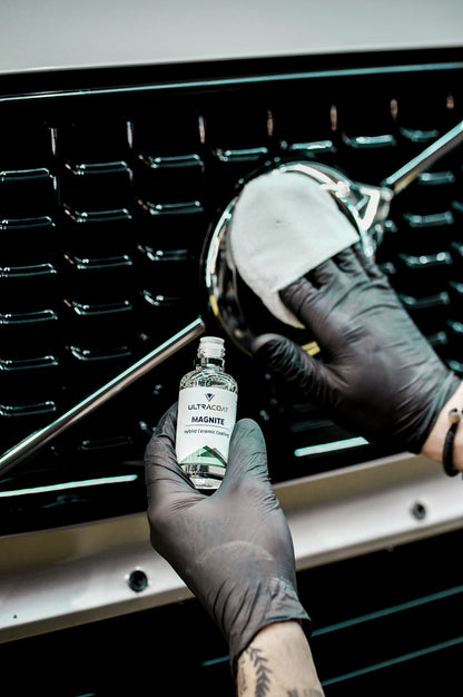 Applying Ultracoat Magnite to a chrome front grille badge with a cloth-wrapped applicator