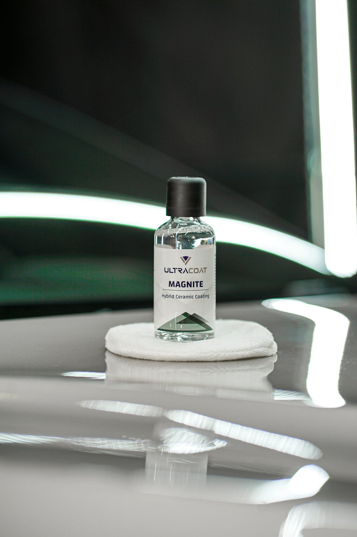Ultracoat Magnite hybrid ceramic coating bottle on an applicator pad, standing on glossy paint