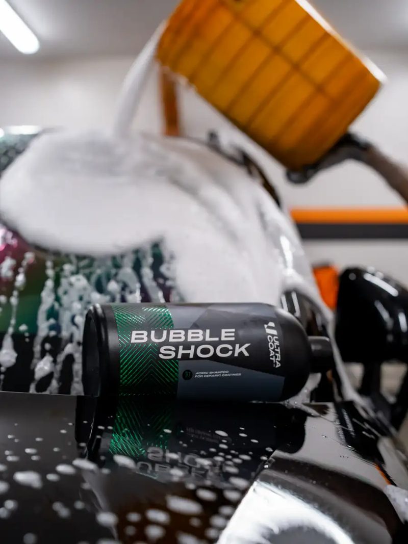 Ultracoat Bubble Shock bottle covered in foam during a service wash on a black panel